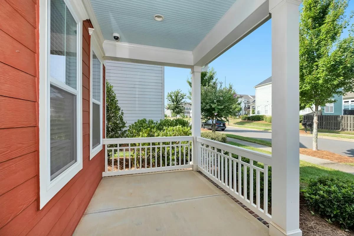 Covered front porch with railings on a red house