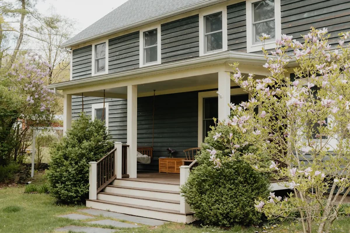 Covered porch on a green house with wide entrance steps
